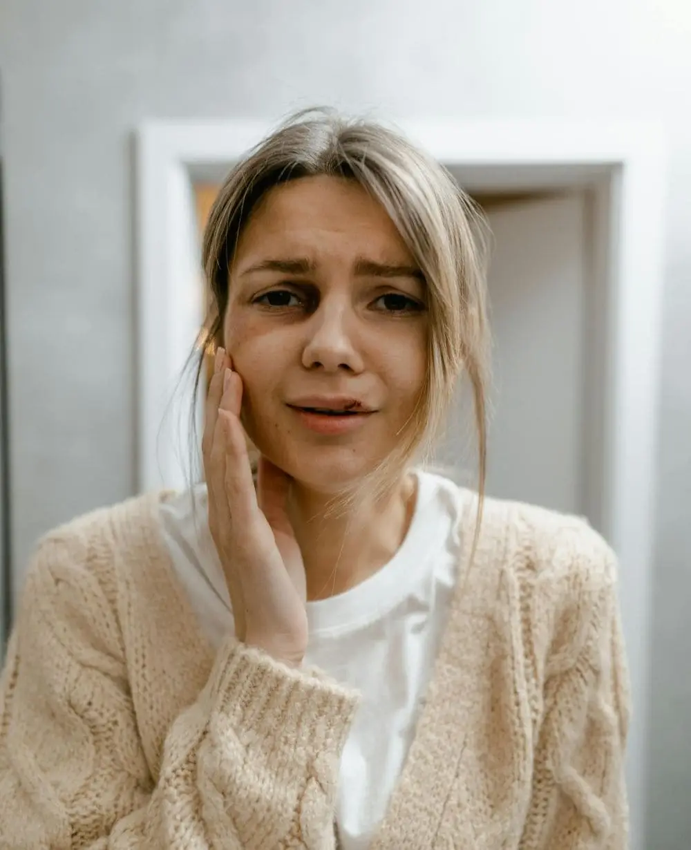 woman with lip injury holding side of face image