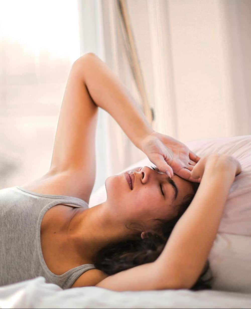 woman in bed with hands on head image